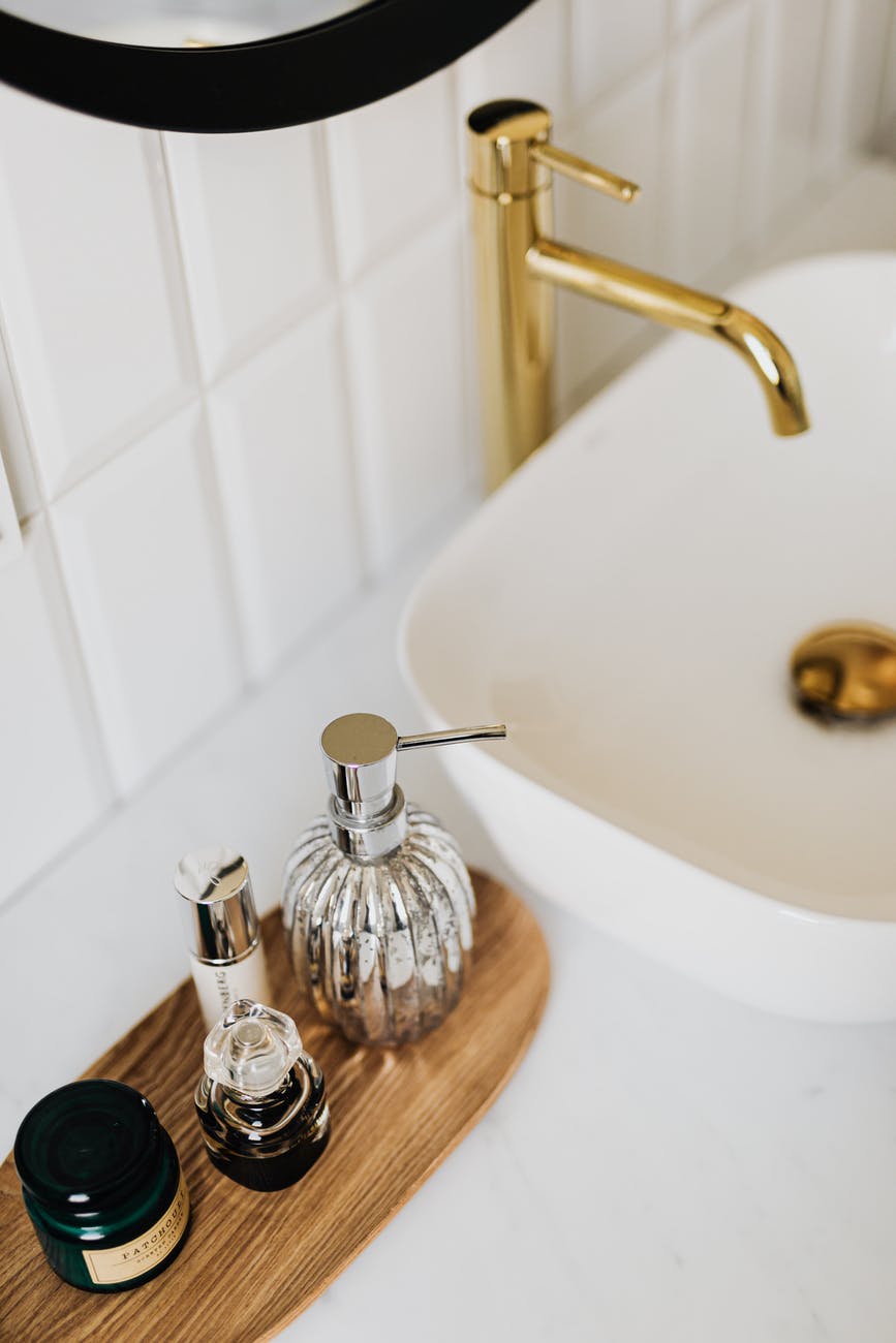 set of stylish cosmetic products placed near sink in bathroom - home cleaning tips